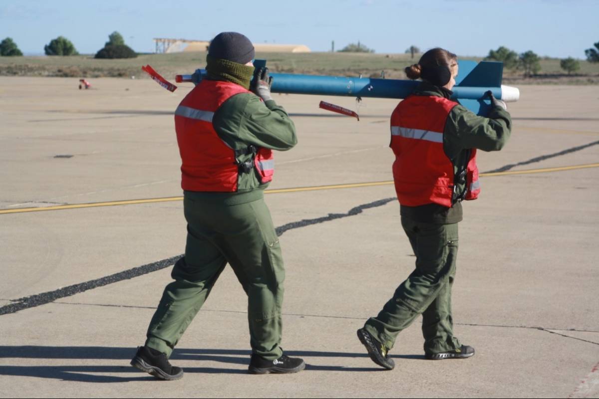 Dos armeros de la Novena Escuadrilla portando un misil de entrenamiento LGTR.